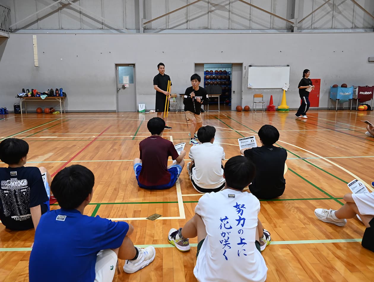 体育館で講師の説明を受ける学生たち