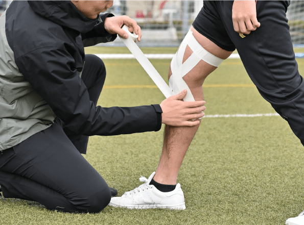 トレーナーが膝にテーピングを施している様子