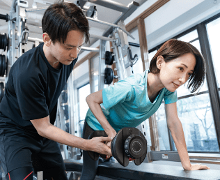 トレーナーがフォームをサポートしながらトレーニング指導を行う様子